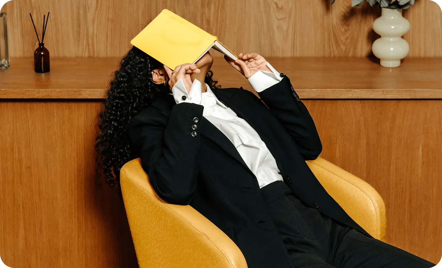 Woman sitting on a chair hiding her face with a book